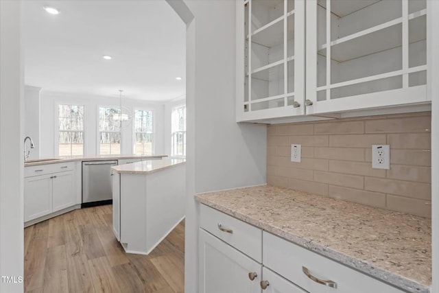 kitchen featuring a sink, white cabinetry, light wood-type flooring, dishwasher, and glass insert cabinets