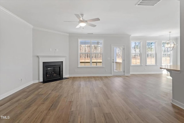 unfurnished living room with wood finished floors, a fireplace with flush hearth, visible vents, and crown molding