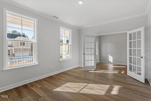 empty room with baseboards, ornamental molding, wood finished floors, and french doors