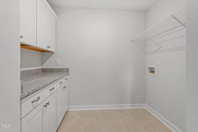 washroom featuring cabinet space, baseboards, washer hookup, and light tile patterned flooring