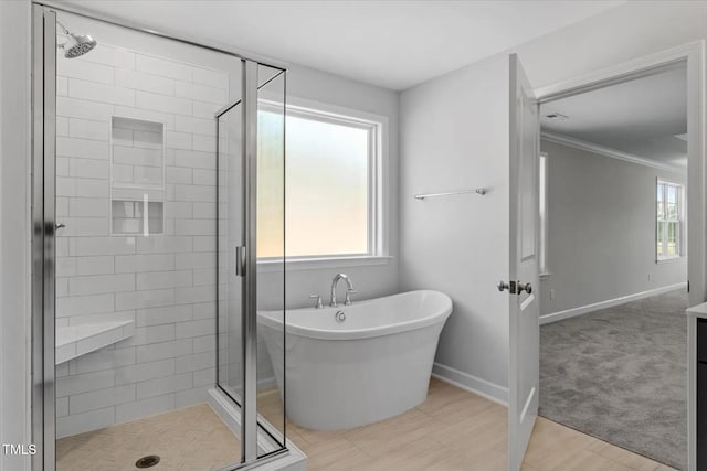 bathroom featuring a freestanding bath, a shower stall, a wealth of natural light, and baseboards