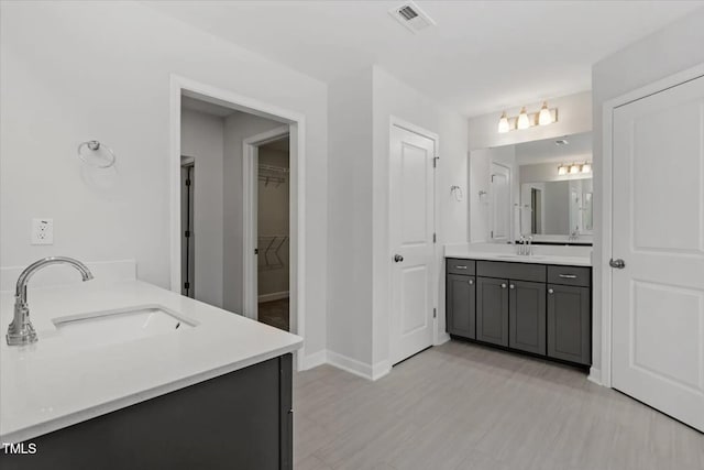 full bathroom featuring two vanities, a sink, visible vents, and baseboards