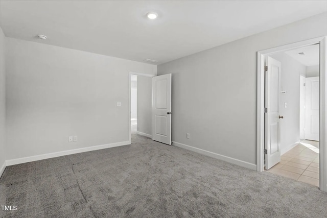 carpeted spare room with baseboards and tile patterned floors