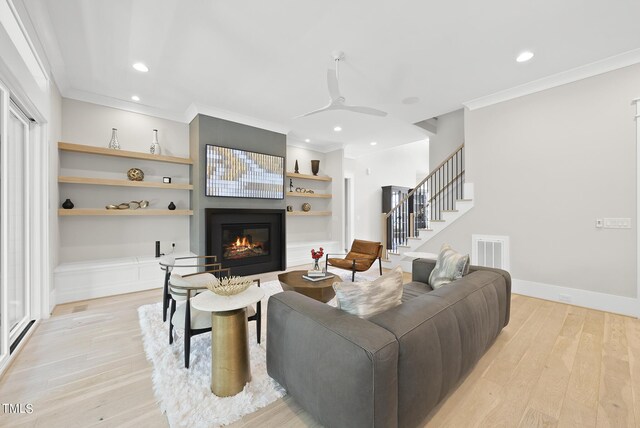 living room featuring built in features, ceiling fan, light hardwood / wood-style floors, and crown molding