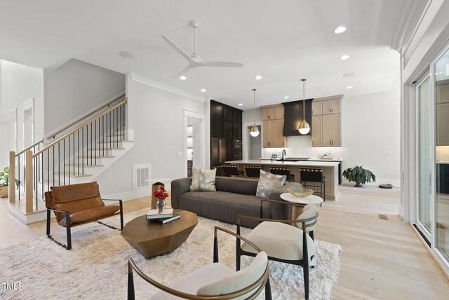 living room with ceiling fan, light hardwood / wood-style flooring, sink, and ornamental molding