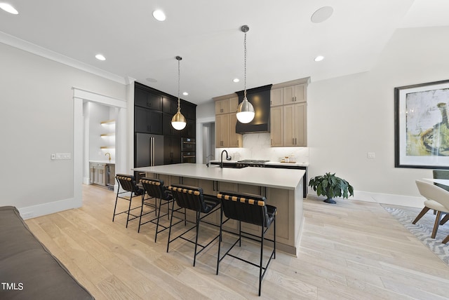 kitchen with custom exhaust hood, light hardwood / wood-style floors, an island with sink, tasteful backsplash, and a breakfast bar area