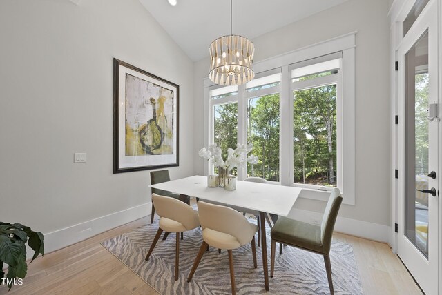 dining area featuring light wood-type flooring, vaulted ceiling, and a chandelier