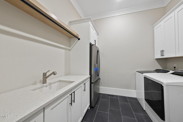 washroom with dark tile patterned flooring, cabinets, crown molding, washer and dryer, and sink