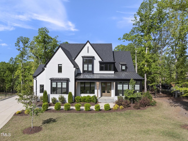 modern farmhouse style home with a front lawn, french doors, fence, metal roof, and a standing seam roof