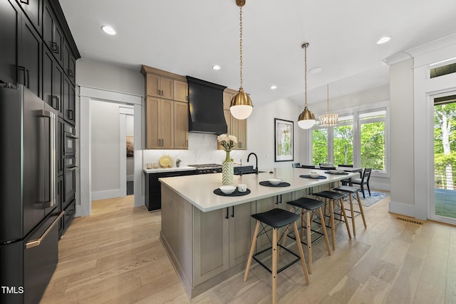 kitchen with custom exhaust hood, stainless steel appliances, light countertops, and light wood-style flooring
