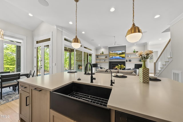 kitchen featuring light countertops, decorative light fixtures, open floor plan, and a sink