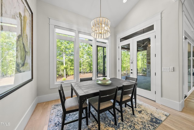 dining room featuring vaulted ceiling, french doors, light wood-style floors, baseboards, and a chandelier