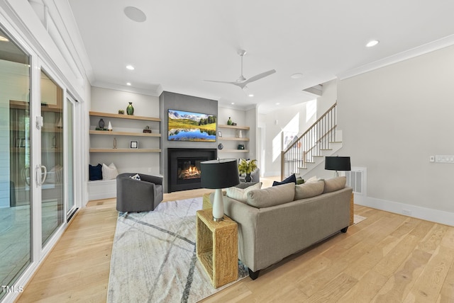 living room with light wood-style floors, stairs, and ornamental molding