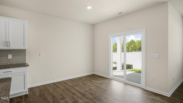 unfurnished dining area with dark wood-type flooring