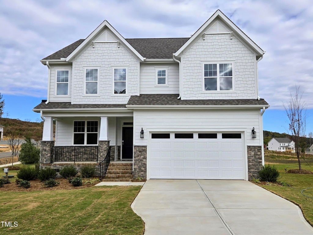 craftsman house featuring a garage, covered porch, and a front lawn