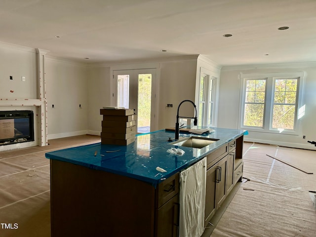 kitchen featuring sink, crown molding, dishwasher, a kitchen island with sink, and dark stone counters