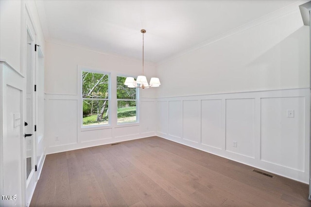 unfurnished dining area featuring dark hardwood / wood-style flooring, ornamental molding, and an inviting chandelier