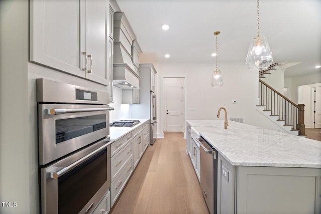 kitchen with appliances with stainless steel finishes, light wood-type flooring, hanging light fixtures, and a large island