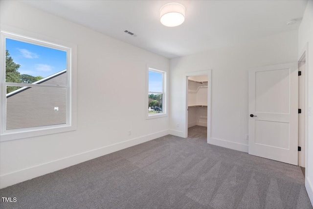 unfurnished bedroom with carpet flooring, a spacious closet, and a closet