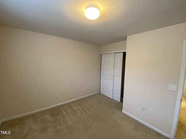 unfurnished bedroom with light carpet and a closet