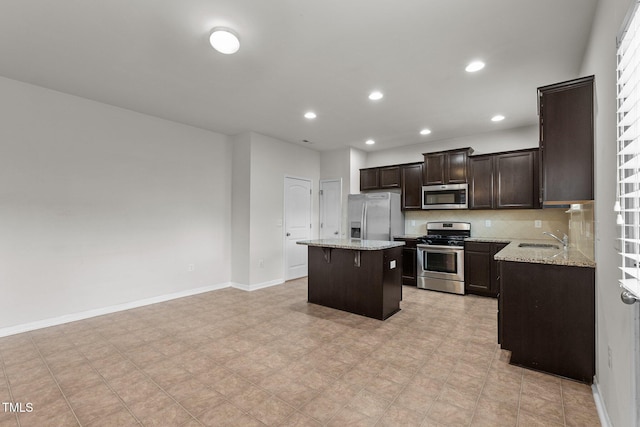 kitchen with sink, tasteful backsplash, a center island, stainless steel appliances, and light stone countertops