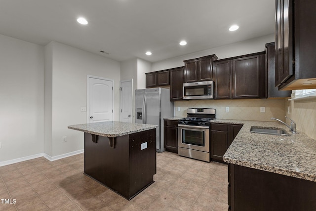 kitchen featuring sink, a kitchen bar, decorative backsplash, a center island, and stainless steel appliances