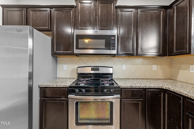 kitchen with tasteful backsplash, light stone countertops, dark brown cabinets, and stainless steel appliances