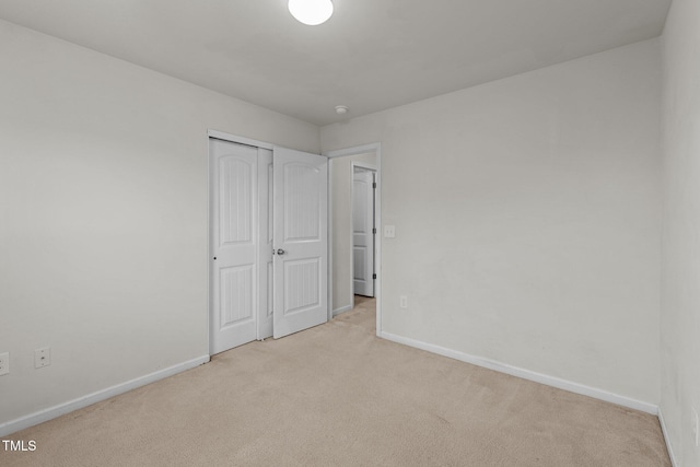 unfurnished bedroom featuring light carpet and a closet