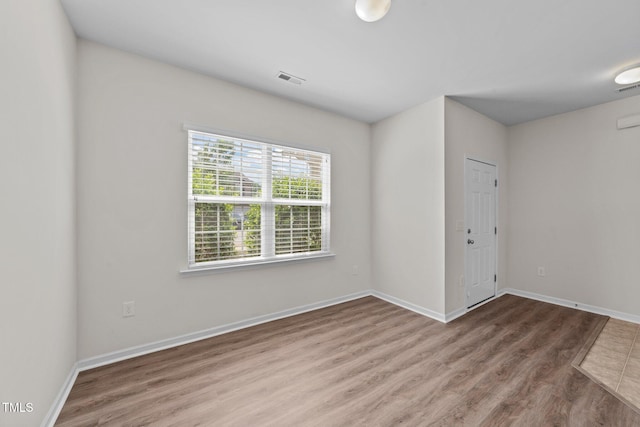unfurnished room with visible vents, baseboards, and wood finished floors