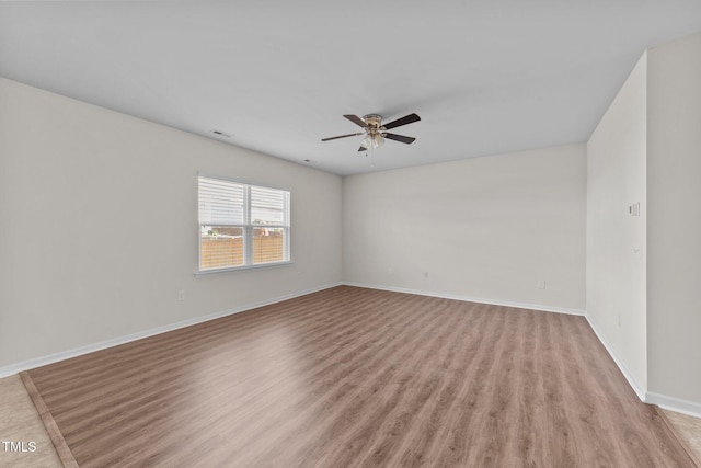 spare room with ceiling fan, visible vents, baseboards, and light wood-style floors