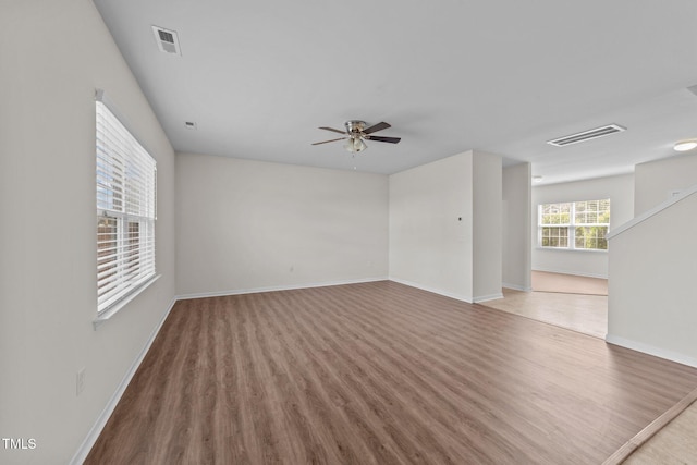 empty room featuring visible vents, baseboards, ceiling fan, and wood finished floors