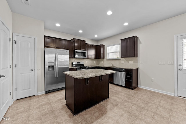 kitchen with decorative backsplash, dark brown cabinetry, a center island, a sink, and appliances with stainless steel finishes