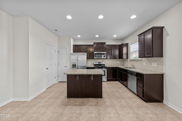 kitchen featuring dark brown cabinets, a sink, stainless steel appliances, backsplash, and a kitchen island