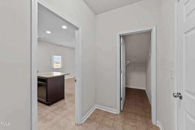 hall featuring baseboards, recessed lighting, and light tile patterned flooring