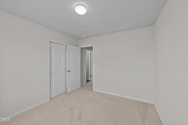 unfurnished bedroom with baseboards, carpet flooring, and a closet