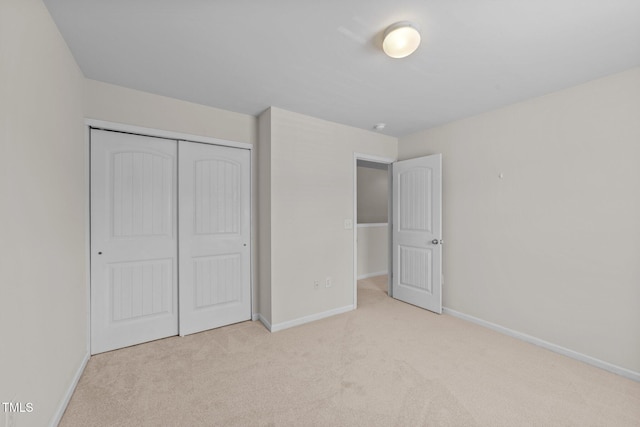 unfurnished bedroom featuring baseboards, carpet, and a closet