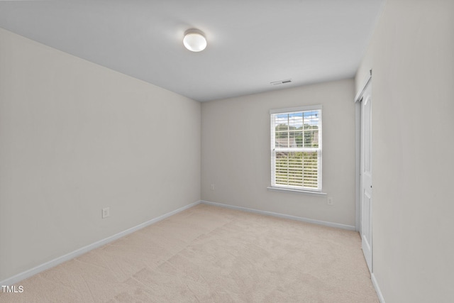 unfurnished room featuring visible vents, baseboards, and light carpet