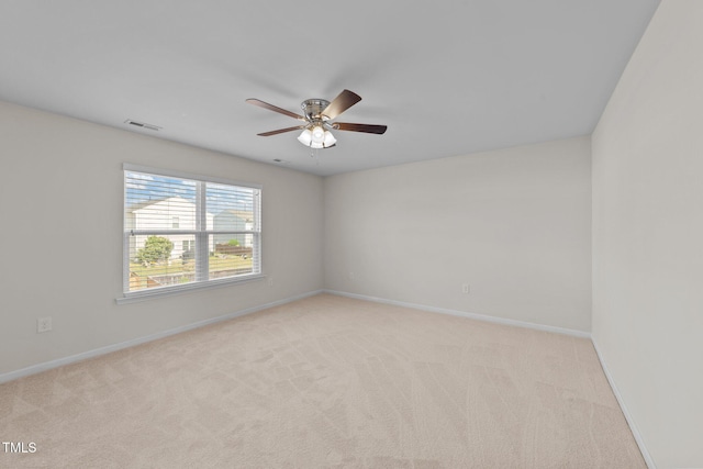 spare room featuring visible vents, a ceiling fan, baseboards, and light colored carpet