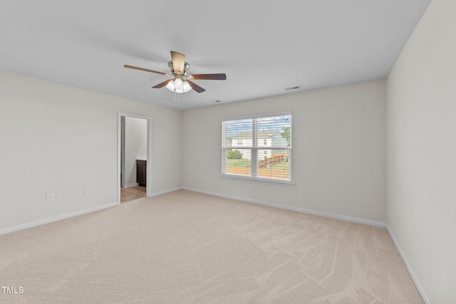 empty room with light colored carpet, a ceiling fan, and baseboards