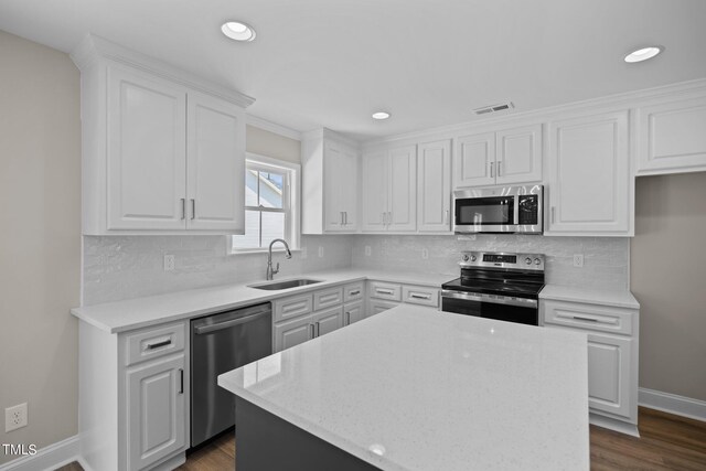 kitchen featuring stainless steel appliances, dark hardwood / wood-style floors, sink, white cabinets, and a center island