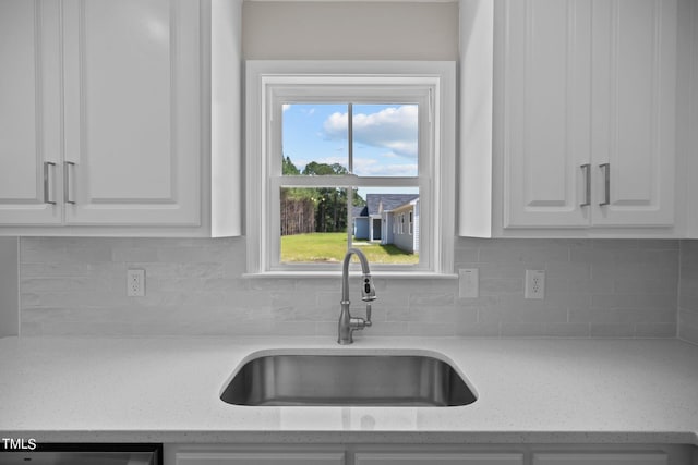 kitchen with tasteful backsplash, dishwasher, light stone countertops, white cabinets, and sink