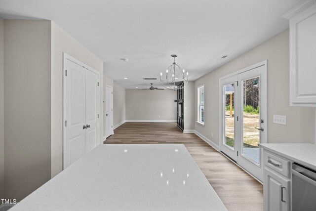 interior space featuring ceiling fan with notable chandelier and light hardwood / wood-style flooring