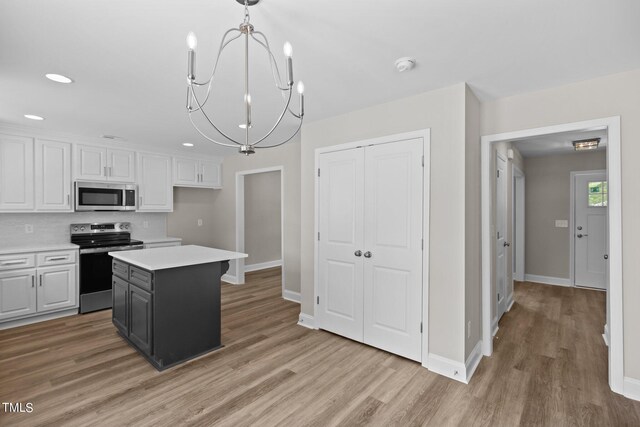 kitchen featuring pendant lighting, a center island, white cabinetry, appliances with stainless steel finishes, and a chandelier