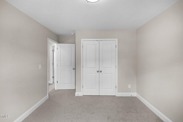 unfurnished bedroom featuring a closet and light colored carpet