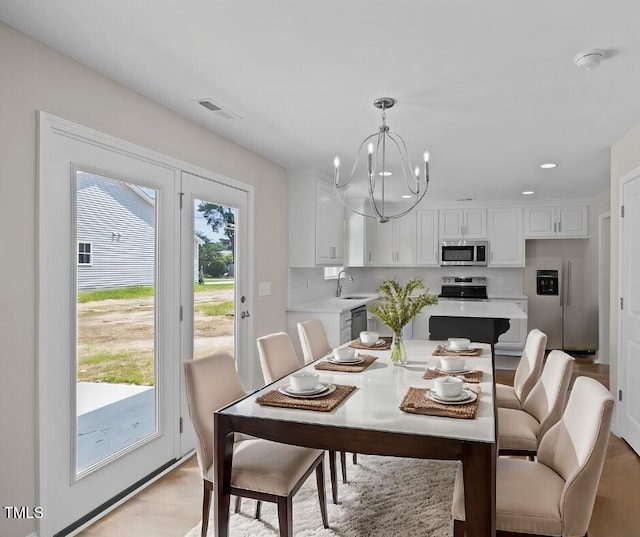 dining area with light hardwood / wood-style floors, sink, and a notable chandelier