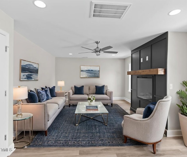 living room with light hardwood / wood-style floors, ceiling fan, and a fireplace