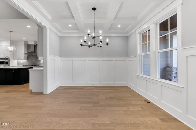 unfurnished dining area featuring light hardwood / wood-style floors, crown molding, beam ceiling, and coffered ceiling