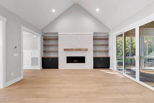 unfurnished living room featuring built in shelves, a fireplace, high vaulted ceiling, and light hardwood / wood-style flooring