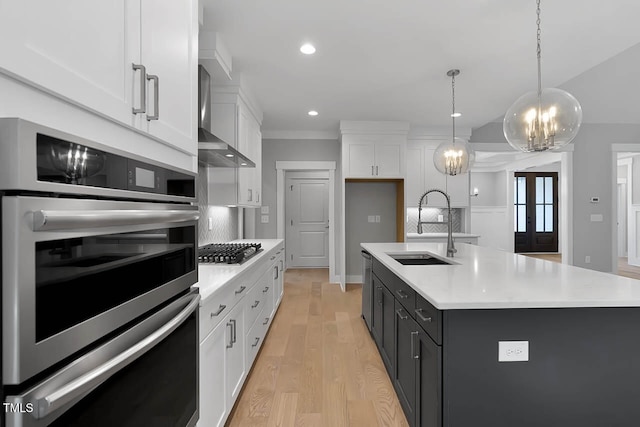 kitchen featuring pendant lighting, a center island with sink, white cabinetry, and sink