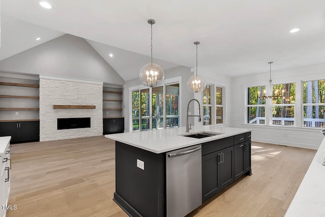 kitchen with pendant lighting, dishwasher, a kitchen island with sink, sink, and vaulted ceiling